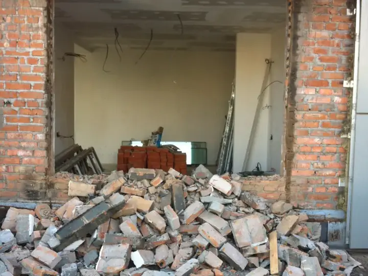 Демонтований широкий проріз у цегляній стіні з металевою балкою над ним
